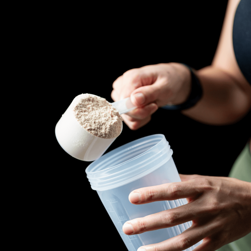 Female athlete holing a scoup of protein powder
